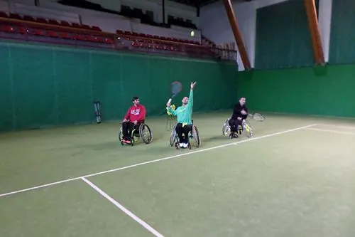 Tennistes en cadira de rodes jugant en una pista coberta